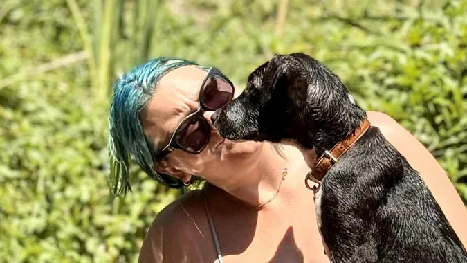 Sarah with Tigger, her Wolfhound x Staffy, as Tigger leans in to lick her cheek